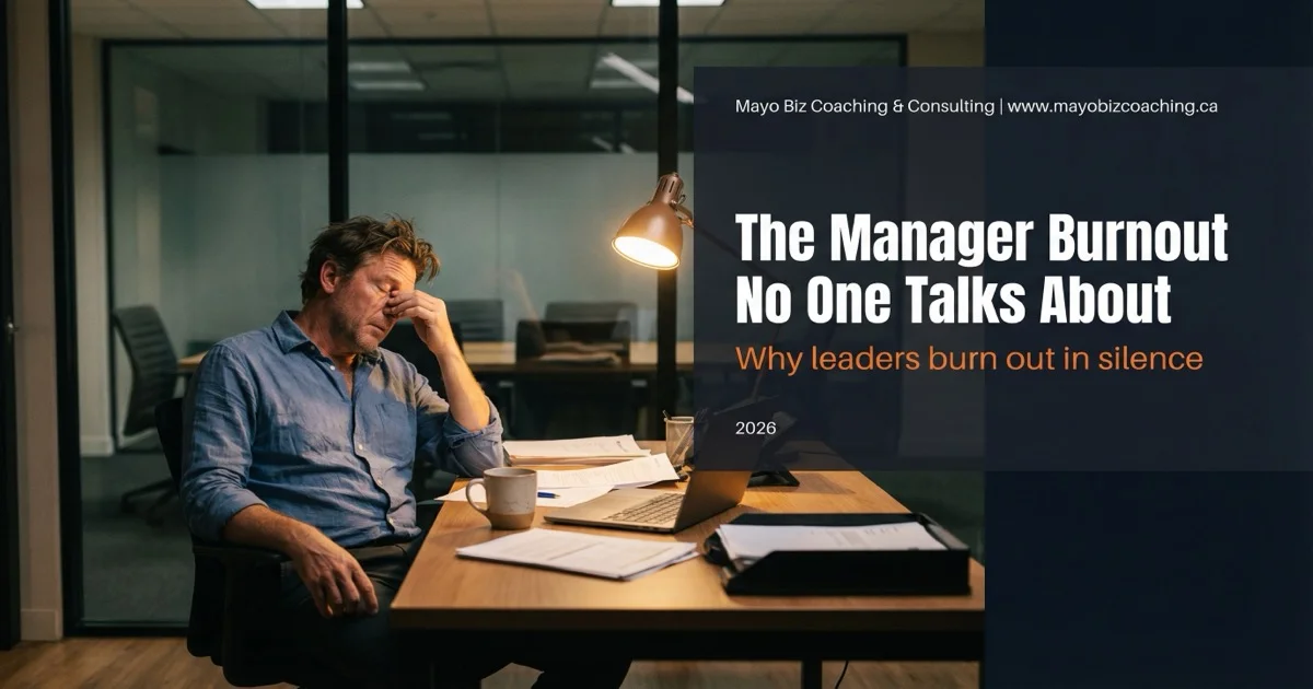 Exhausted manager alone at a desk with an empty meeting room behind them, warm lighting through office windows